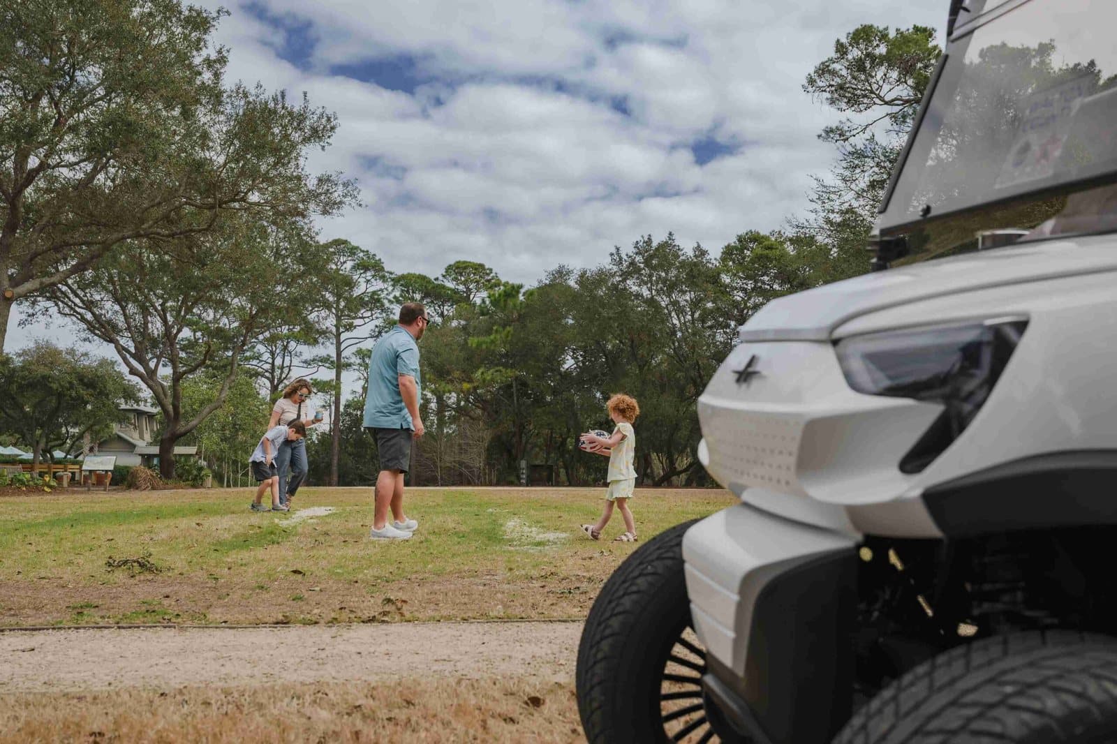 A white Electric Cart Company golf cart cruising a scenic 30A beach road on a sunny day